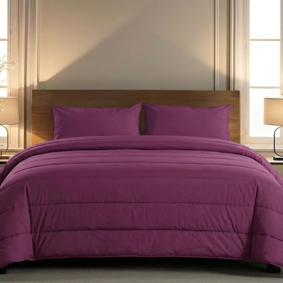 Een keurig opgemaakt bed met een houten hoofdeinde, pruimkleurig beddengoed en bijpassende kussens kenmerkt het Zelesta Comfort Uni Dekbed in Bordeaux, geflankeerd door twee nachtkastjes met lampen.