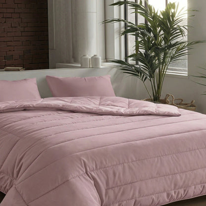 Een netjes opgemaakt bed met het Zelesta Comfort Uni Dekbed - Oud Roze en bijpassende kussens in een moderne slaapkamer met grote ramen, een potplant en een bakstenen accentmuur - ideaal voor klassieke dekbedden of als dekbed voor het hele seizoen.