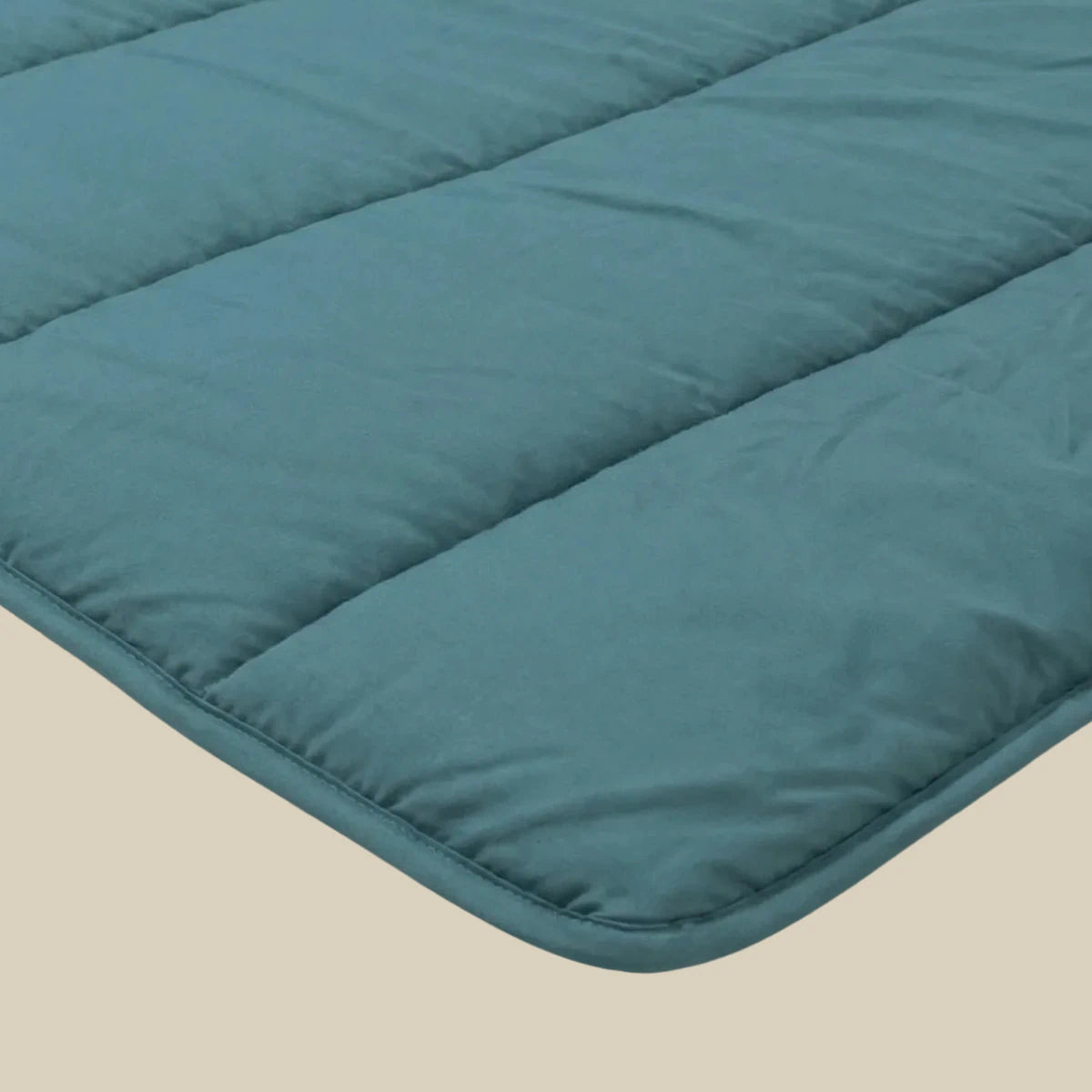 Een close-up van het Zelesta Comfort Uni Dekbed in zeegroen, met horizontale quilting, getoond op een beige oppervlak.