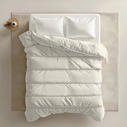 Een netjes opgemaakt bed met het Zelesta Everyday Uni Dekbed - Crème en twee kussens, met daarop een wit dekbed, staat op een beige vloerkleed naast een klein rond houten nachtkastje met een decoratief item.