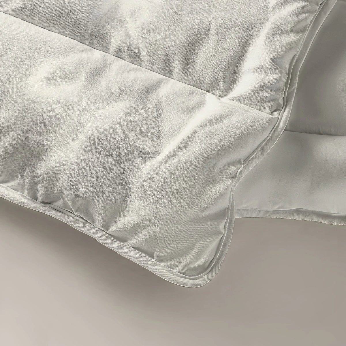 Een crèmekleurige deken op een wit oppervlak, met het Zelesta Everyday Uni Dekbed - Crème voor comfort het hele jaar door.