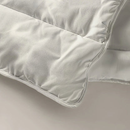 Een crèmekleurige deken op een wit oppervlak, met het Zelesta Everyday Uni Dekbed - Crème voor comfort het hele jaar door.