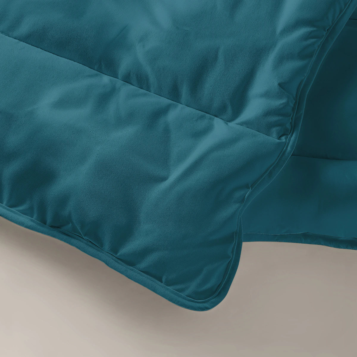 Een close-up van het Zelesta Everyday Uni Dekbed in diep marineblauw met gewatteerde stiksels, gedrapeerd op een lichte ondergrond - een dekbed en overtrek voor alle seizoenen in één.