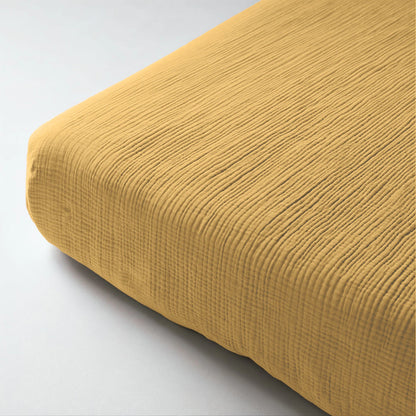 Close-up van de Mousseline Hoeslaken - Okergeel in mousseline katoen, met een subtiel rasterpatroon en ademend bedcomfort voor je matras.