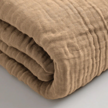 Een close-up van de Mousseline Hoeslaken in taupe, met een gestructureerde, lichtbruine katoenmix - ideaal voor wie op zoek is naar ademend beddengoed.