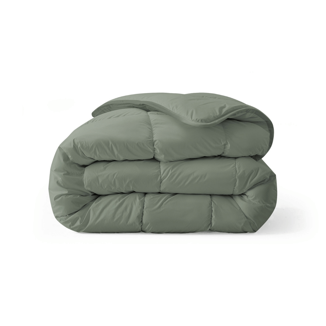 Het Zelesta Royalbed - Pastel Green is een gevouwen, all-season dekbed met een gladde, gezwollen textuur, afgebeeld tegen een effen witte achtergrond.