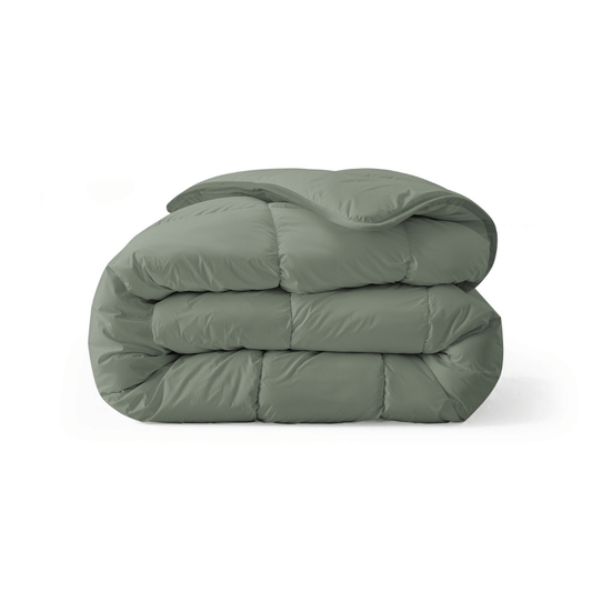 Het Zelesta Royalbed - Pastel Green is een gevouwen, all-season dekbed met een gladde, gezwollen textuur, afgebeeld tegen een effen witte achtergrond.