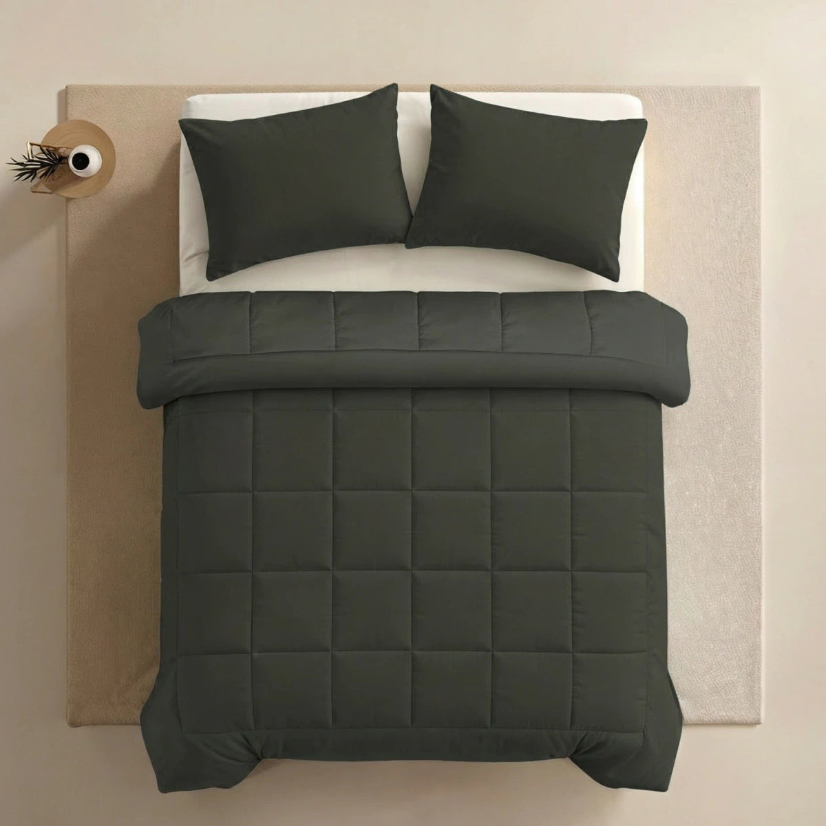 Een keurig opgemaakt bed met de Zelesta Pure Uni Dekbed Katoen in olijfzwart, bijpassende kussens en een wit laken is van bovenaf te zien; op een bijzettafeltje staat een vaas - een perfecte keuze voor slaapcomfort en fans van duurzame dekbedden.