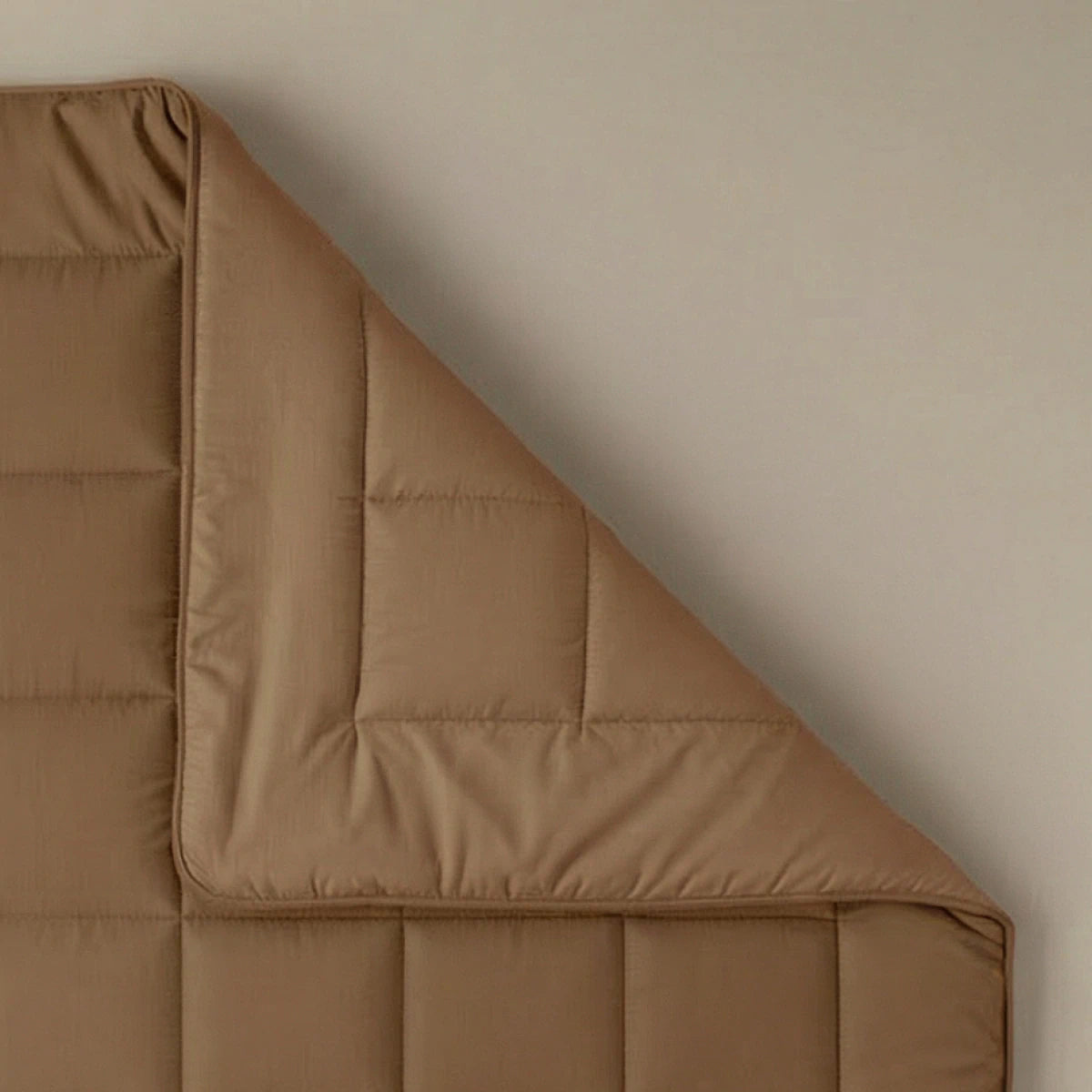 De Zelesta Pure Uni Dekbed Katoen - Cacao Bruin is netjes in één hoek gevouwen op een effen oppervlak en biedt een ademend slaapcomfort voor een rustgevende nacht.
