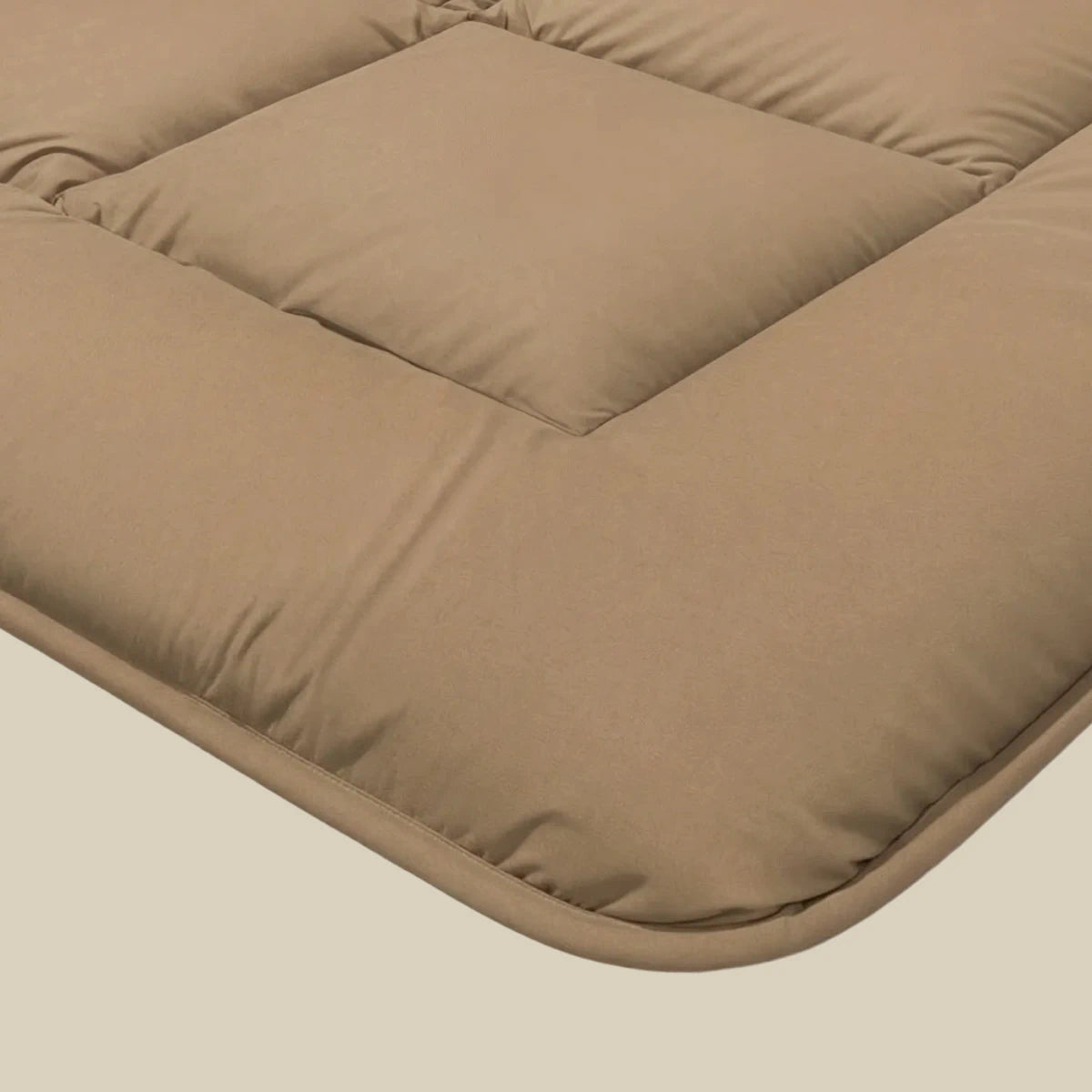 Close-up van een lichtbruin, gewatteerd kussen met afgeronde hoeken en zichtbare stiksels, ontworpen voor ademend slaapcomfort - perfect in combinatie met de Zelesta Pure Uni Dekbed Katoen in Cacao Bruin.
