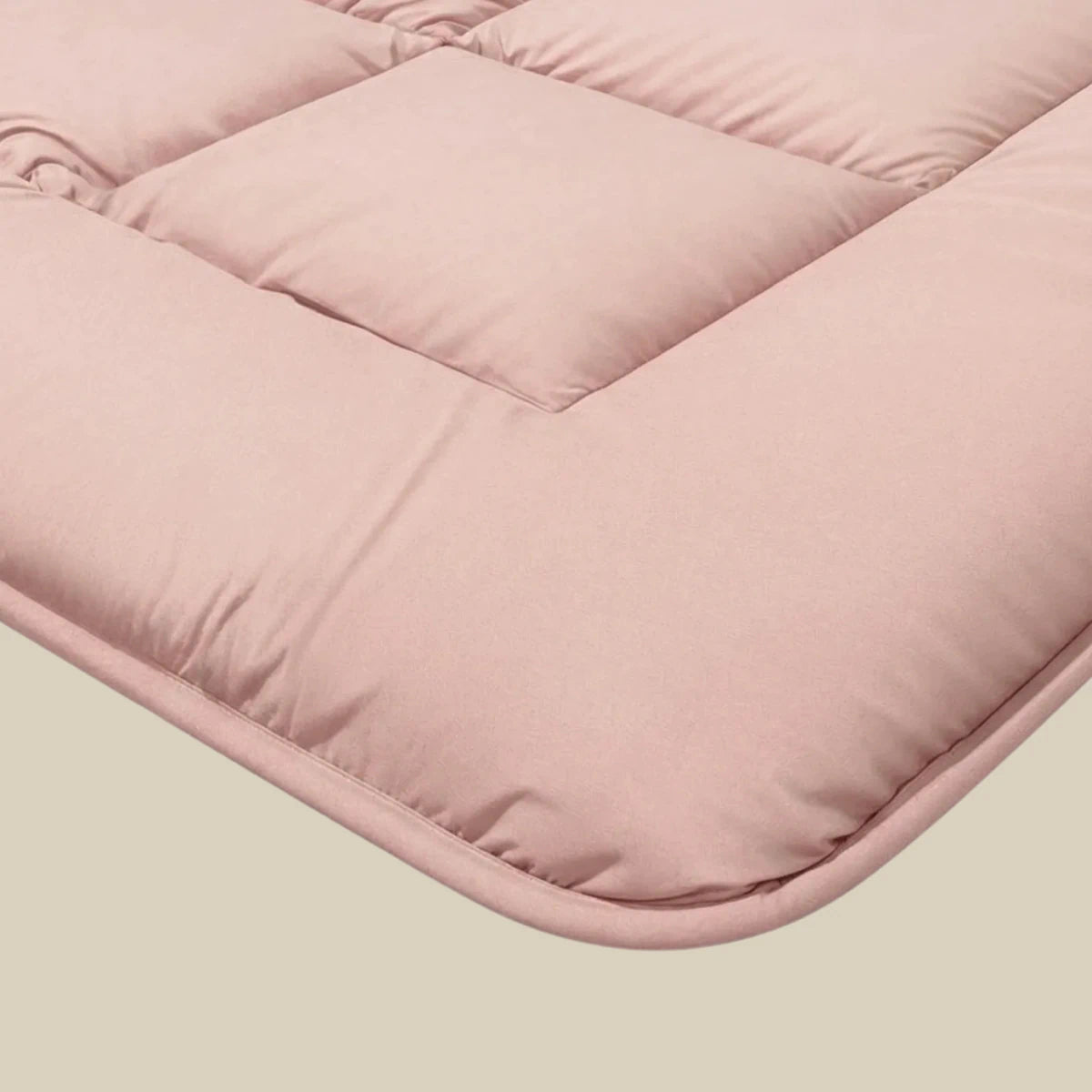 Close-up van de Zelesta Pure Uni Dekbed Katoen in zachtroze, met doorgestikte stiksels en een gewatteerde textuur voor geavanceerd slaapcomfort, ideaal om te combineren met duurzaam beddengoed.