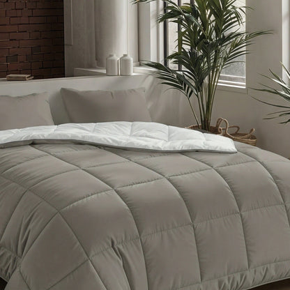 Een netjes opgemaakt bed met de Zelesta Pure Uni Dekbed Katoen - Antraciet Grijs, witte lakens, twee kussens en een plant bij het raam in een moderne, minimalistische slaapkamer voor ademend slaapcomfort.