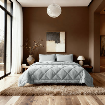 Een moderne slaapkamer met een netjes opgemaakt bed met het Zelesta Comfort Uni diamond Dekbed in grijsblauw, neutraal beddengoed, donzig vloerkleed, bruine muren, abstract kunstwerk, groot raam met transparante gordijnen en decoratieve accessoires aan de bijzettafel.