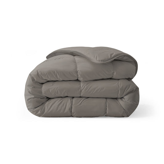 Een netjes opgevouwen, grijs dekbed met een doorgestikt dessin op een witte achtergrond - dit Zelesta Royalbed - Tender Grey doet dienst als dekbed en overtrek in één en biedt het hele jaar door comfort en gemak.