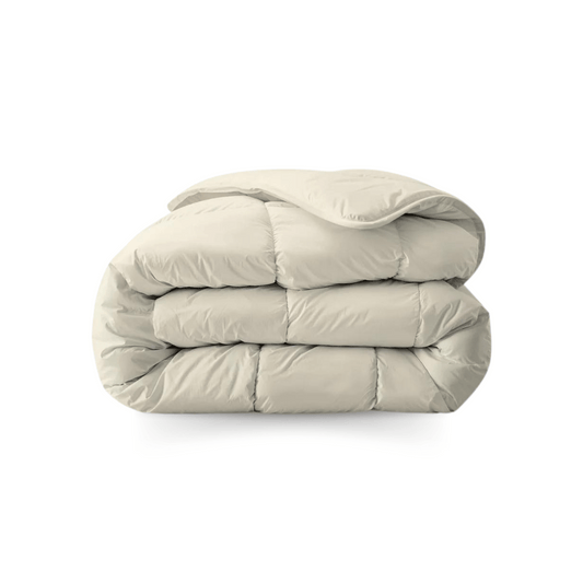 Een netjes opgevouwen, lichtbeige dekbed van zachte, doorgestikte stof op een witte ondergrond - een Zelesta Royalbed - Sand Beach dekbed en overtrek in één voor comfort het hele jaar door.