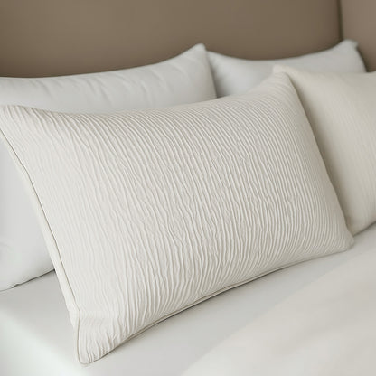 Close-up van een netjes opgemaakt bed met witte structuurkussens en frisse lakens tegen een beige hoofdeinde, met het Zelesta Velvetbed Chique Kussensloop Set van 2 - Beige voor extra comfort.