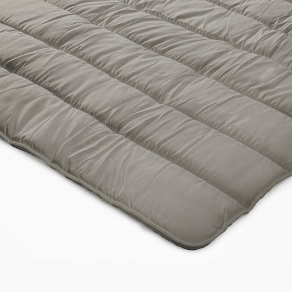 Een close-up van het Zelesta Royalbed - Tender Grey, een dekbed en overtrek voor alle seizoenen in één, met een grijs gewatteerd dekbed plat gelegd op een witte ondergrond.