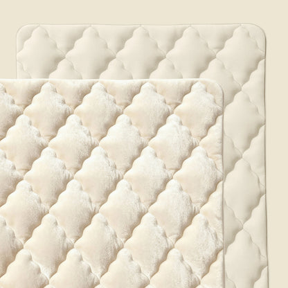 Een close-up van twee doorgestikte, crèmekleurige matrasbeschermers met een ruitpatroon, overlappend op een beige achtergrond - ideaal om te combineren met de Zelesta Flanel Uni - Beige.