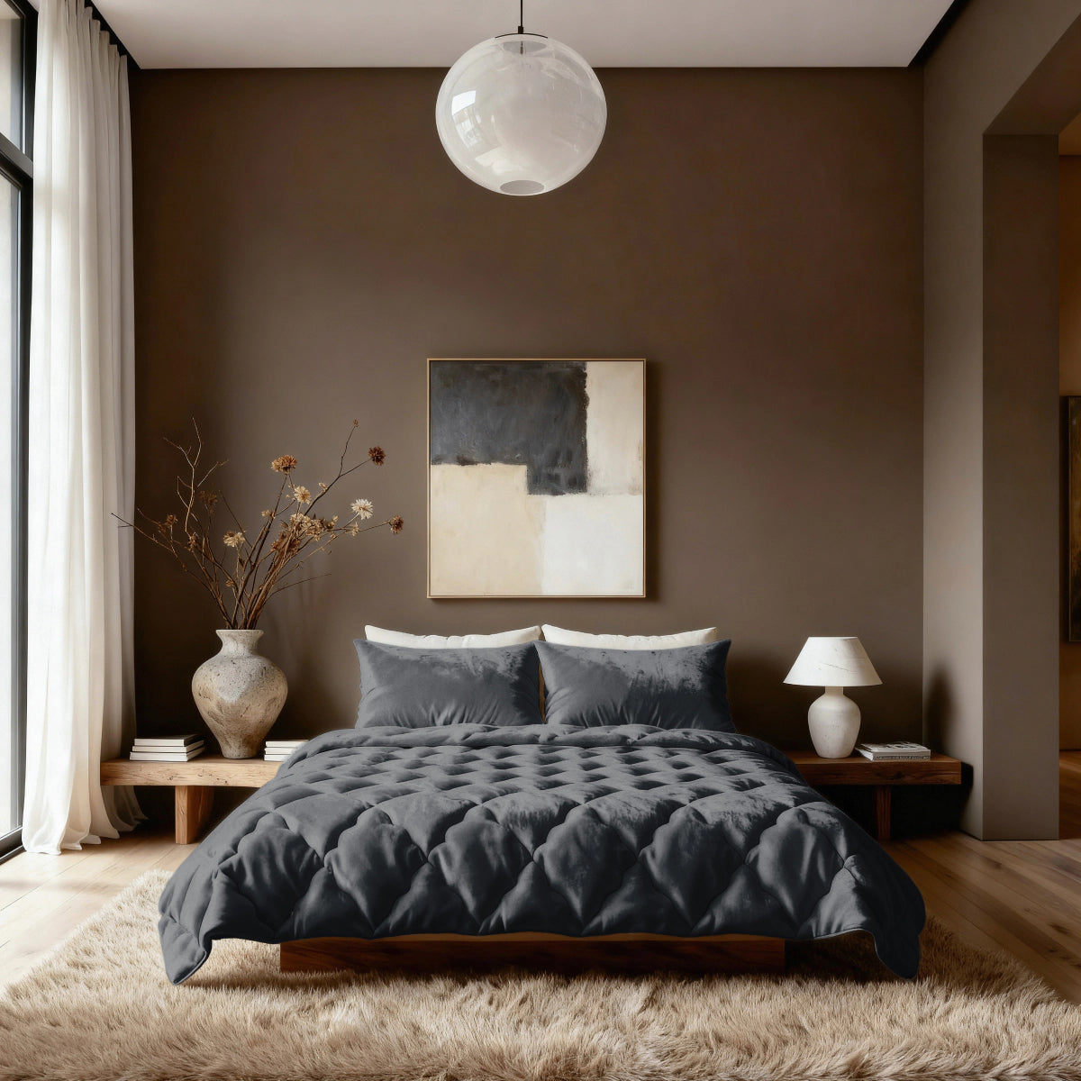 Een moderne slaapkamer met het Zelesta Flanel Uni - Zwart 2-in-1 dekbed op een laag houten bed, met beige muren, een groot abstract schilderij, vazen met gedroogde takken, een tafellamp en een ronde plafondlamp boven een pluche vloerkleed.