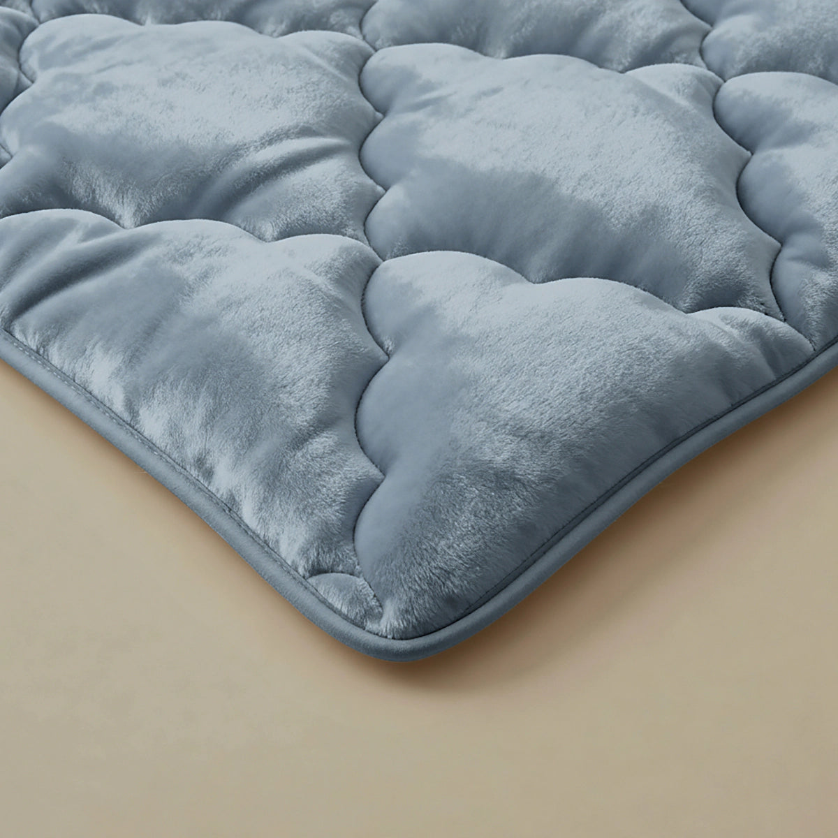 Een close-up van het pluche Zelesta Flanel Uni - Blue Mirage dekbed, met een zachte, fluweelachtige textuur en wolkachtig patroon in lichtblauw, op een neutraal beige oppervlak.
