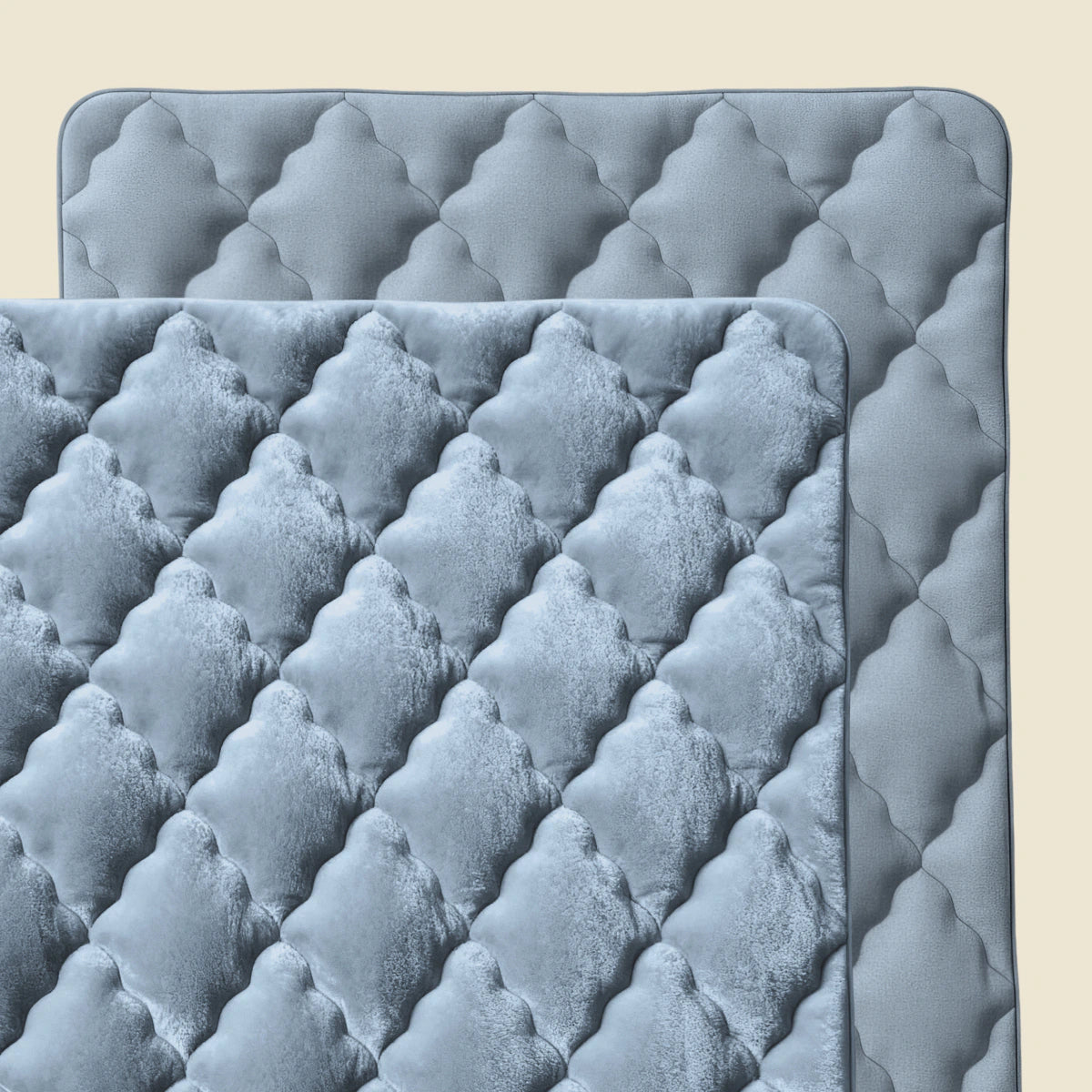 Twee overlappende Zelesta Flanel Uni - Blue Mirage gewatteerde matten met een ruitpatroon en afgeronde hoeken op een lichtbeige achtergrond. Deze matten hebben een zachte, gewatteerde textuur - ideaal als temperatuurregulerend dekbed het hele jaar door.