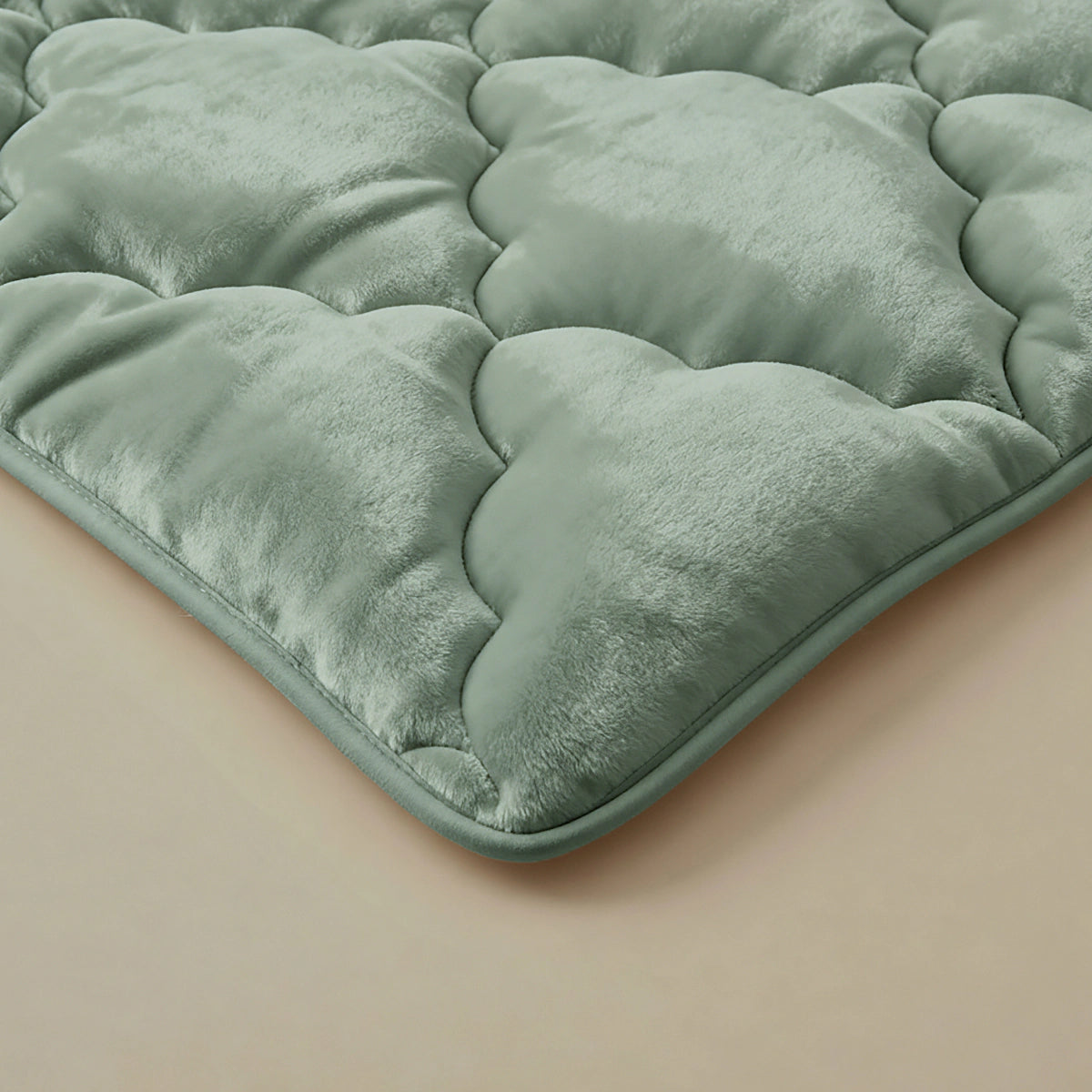 Een close-up van het Zelesta Flanel Uni dekbed in groen, met een zachte, gewatteerde textuur en rustend op een lichtbeige oppervlak.