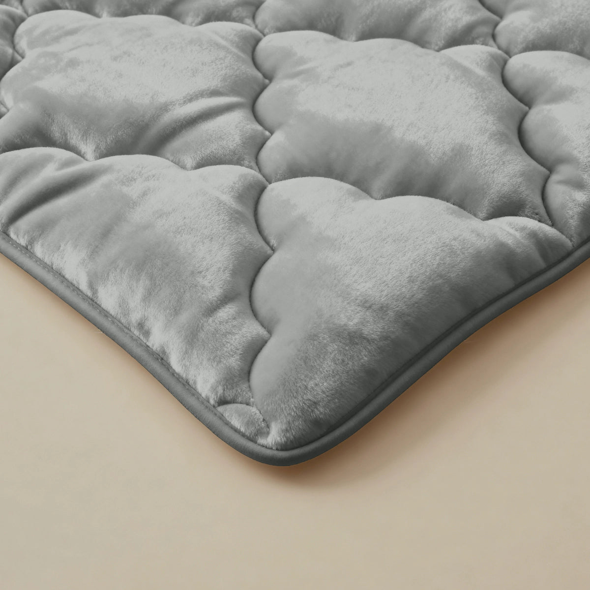 Close-up van de Zelesta Flanel Uni - Kaki matrasmatras, met een zacht, gewatteerd microvezelontwerp met pluche textuur en afgeronde stiksels, getoond op een beige oppervlak.
