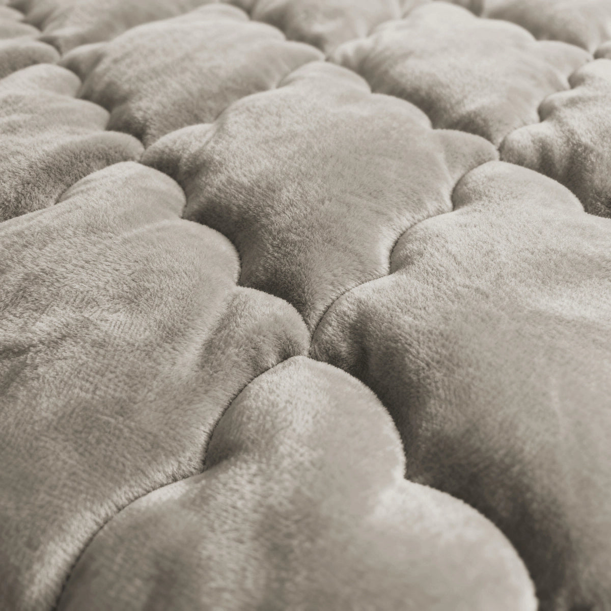 Close-up van het Zelesta Flanel Uni - Taupe dekbed: het zachte, gewatteerde oppervlak heeft wolkachtige patronen in licht taupe, een gladde fluweelachtige textuur en biedt temperatuurregulerend comfort.