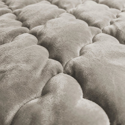 Close-up van het Zelesta Flanel Uni - Taupe dekbed: het zachte, gewatteerde oppervlak heeft wolkachtige patronen in licht taupe, een gladde fluweelachtige textuur en biedt temperatuurregulerend comfort.