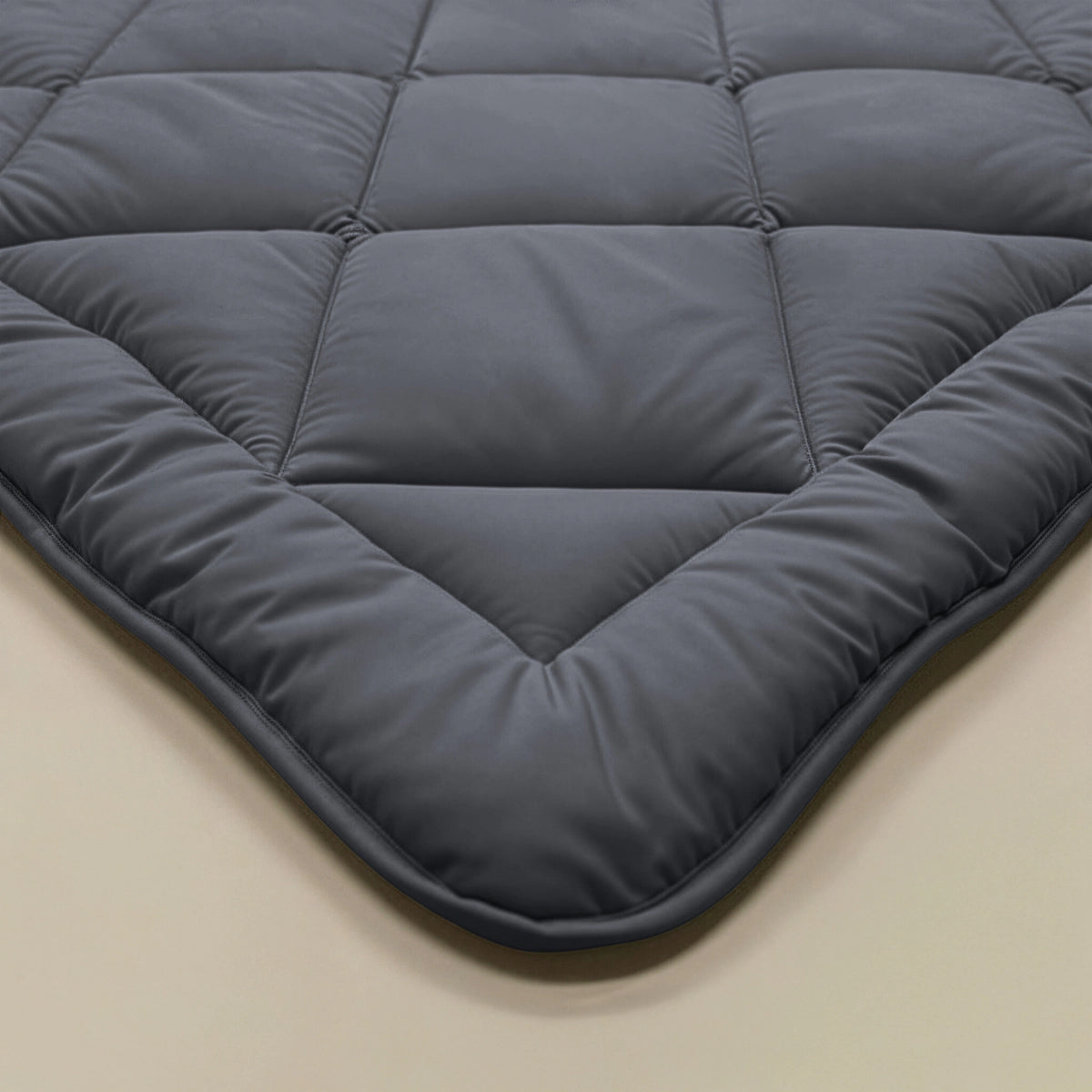 Een close-up van een hoek van het Zelesta Comfort Uni diamond Dekbed in antraciet, met doorgestikte details op een licht oppervlak.