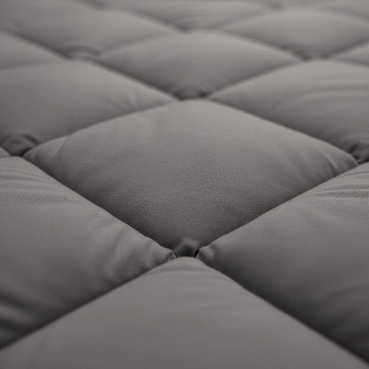 Close-up van het Zelesta Comfort Uni diamond Dekbed in bruin-grijs, met een gewatteerd oppervlak met gelijkmatig verdeelde gepolsterde vierkanten die doen denken aan klassieke dekbedden en het hele seizoen comfort bieden.