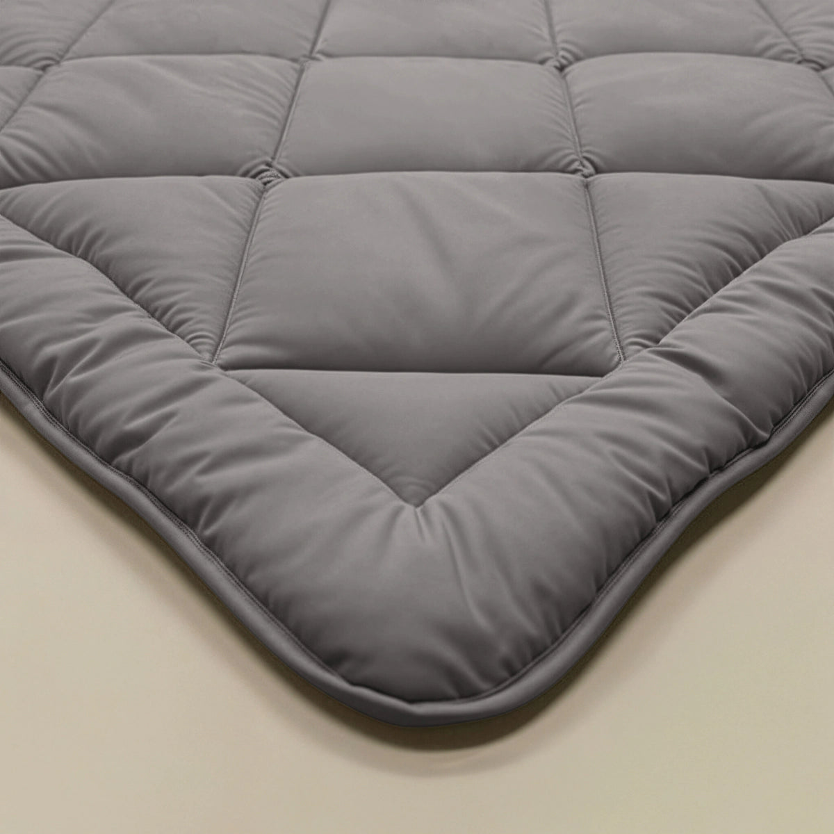 Close-up van het Zelesta Comfort Uni diamond Dekbed in bruin-grijs, met een ruitpatroon geïnspireerd op klassieke dekbedden. Afgebeeld op een beige oppervlak, is het een laag voor alle seizoenen met een stijlvol, praktisch ontwerp.