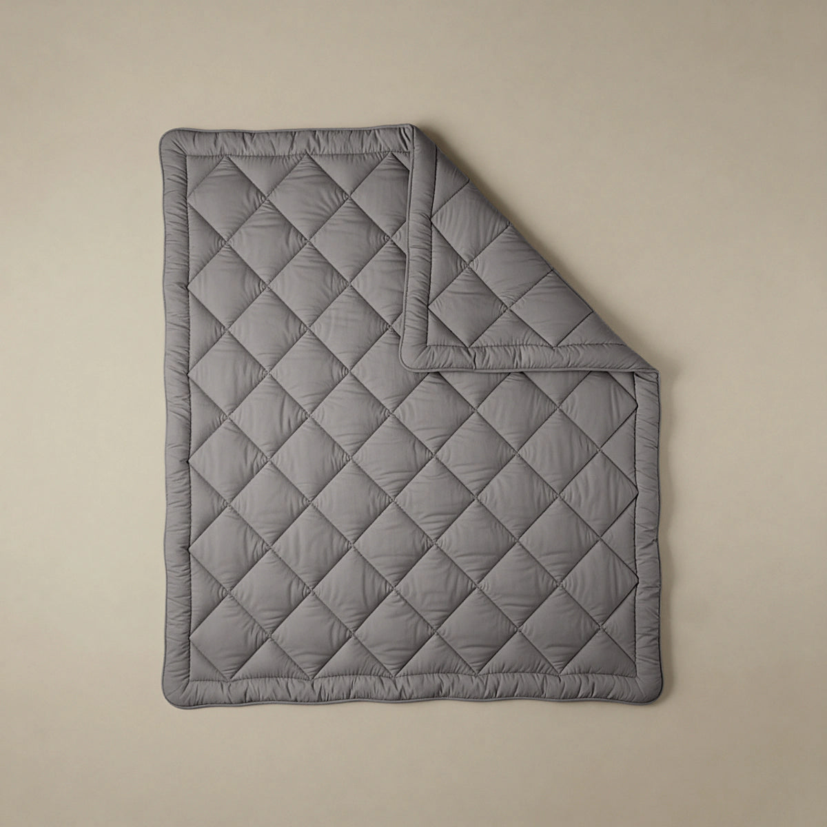 Het Zelesta Comfort Uni diamond Dekbed in bruin-grijs, geïnspireerd op klassieke dekbedden, heeft een doorgestikt ruitpatroon en wordt plat getoond op een neutrale achtergrond met één hoek omgeslagen.