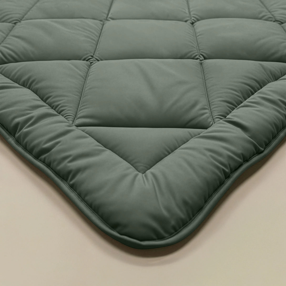 Close-up van een hoek van het Zelesta Comfort Uni diamond Dekbed in groen, met het doorgestikte ontwerp en de zachte, gladde textuur die doet denken aan klassieke dekbedden.