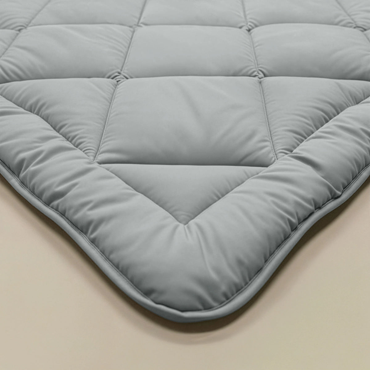 Close-up van het Zelesta Comfort Uni diamond Dekbed in grijs-blauw, met een doorgestikt ruitpatroon van de Comfort-lijn, getoond op een beige ondergrond.