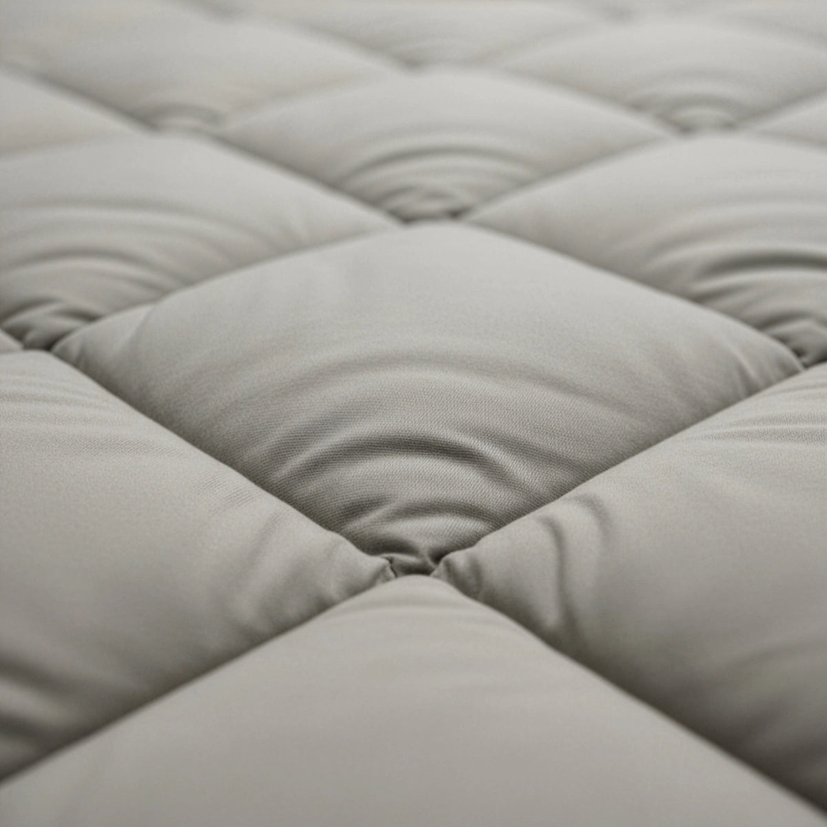 Close-up van het Zelesta Comfort Uni diamond Dekbed - Zandbeige, met gewatteerde, gewatteerde stof met ruitvormige stiksels en zachte, verhoogde delen geïnspireerd op klassieke dekbedden.