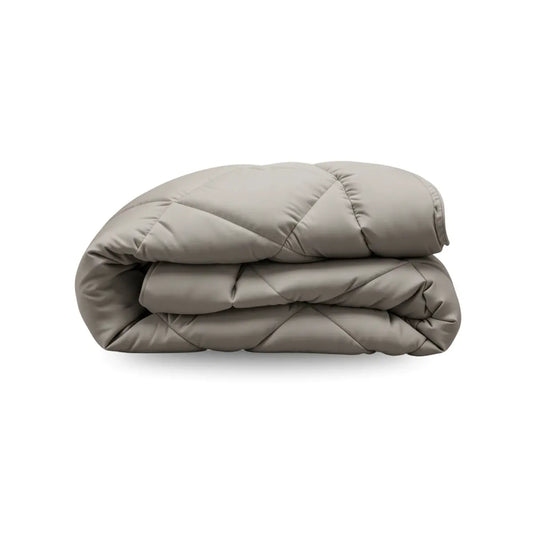 Een zandbeige, ruitgequilte Zelesta Comfort Uni Dekbed is netjes gevouwen tegen een witte achtergrond.