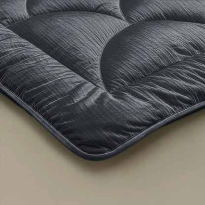 Close-up van de hoek van het Zelesta Flanel Velvetbed Chique in Antraciet, met het donkergrijze, doorgestikte ontwerp met een glad, gestructureerd oppervlak op een lichte achtergrond.
