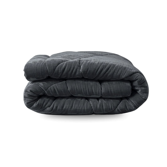 Het Zelesta Flanel Velvetbed Chique in antraciet, met een doorgestikte fluwelen textuur, wordt getoond opgevouwen tegen een witte achtergrond.