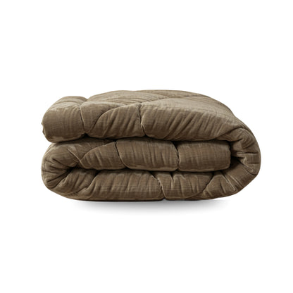 Het Zelesta Flanel Velvetbed Chique in taupe is een dik, luxe fluwelen dekbed, netjes opgevouwen op een witte ondergrond.