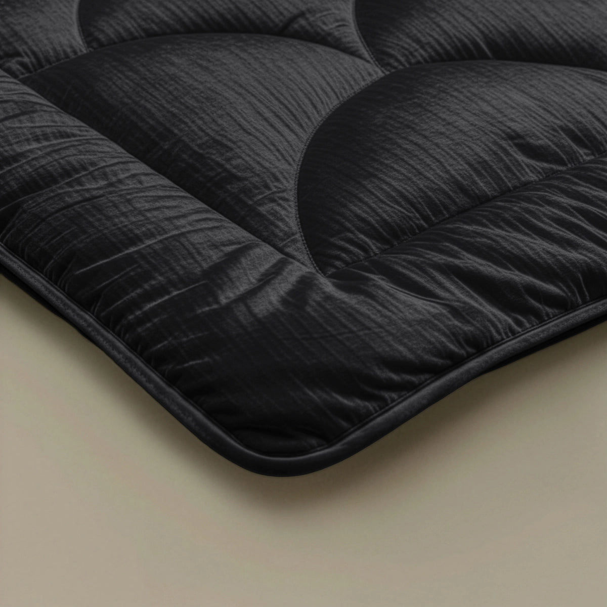 Close-up van de hoek van het Zelesta Flanel Velvetbed Chique - Black, een doorgestikt, temperatuurregulerend dekbed met een luxe uitstraling op een lichte ondergrond.