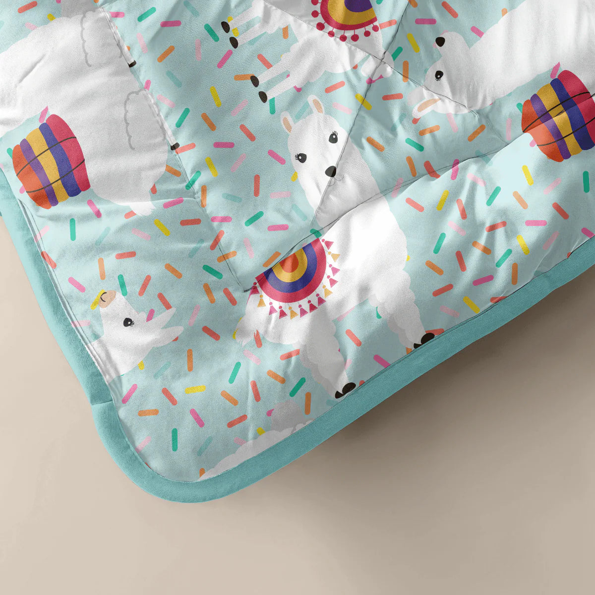 Het Zelesta Kiddybed - Party Lama is een hypoallergeen kinderdekbed met een lichtblauwe rand, witte lama-illustraties, kleurrijke dekens en veelkleurige strooipatronen - ideaal voor knusse nachten.